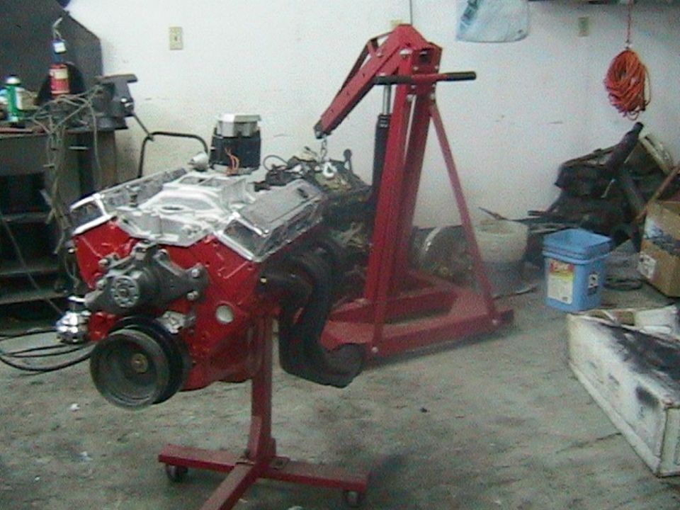 Red V8 engine on a red engine stand in a garage