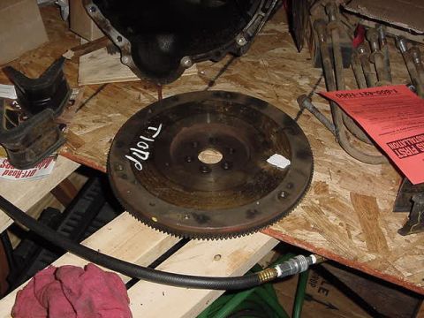 1995 Ford Bronco - A close-up view of a vehicle's flywheel and transmission bell housing, with some tools and a red instruction sheet in the background.