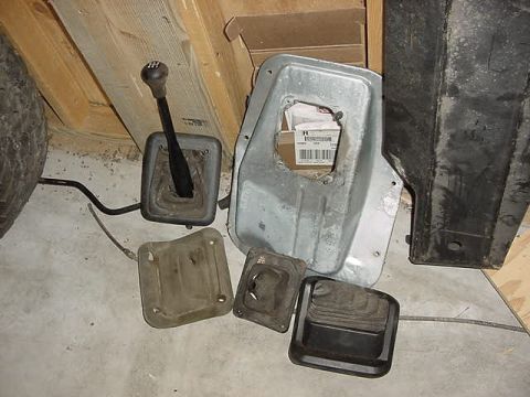 1995 Ford Bronco - Various parts of a vehicle's transmission and shifter system are laid out on the floor.