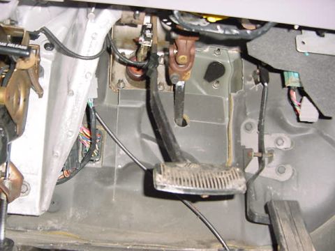 1995 Ford Bronco - Close-up view of the interior footwell, showing the brake and gas pedals along with visible wiring and mechanical components.