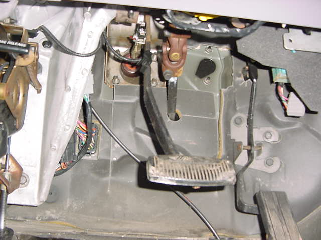Interior footwell with brake and gas pedals, wiring visible
