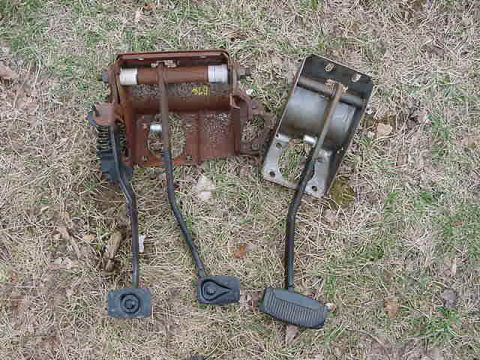 1995 Ford Bronco - A rusty pedal assembly with three pedals is shown lying on the ground.