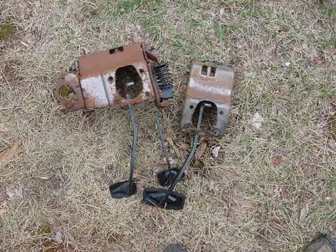 1995 Ford Bronco - Two rusty brake and clutch pedal assemblies lie on the ground.
