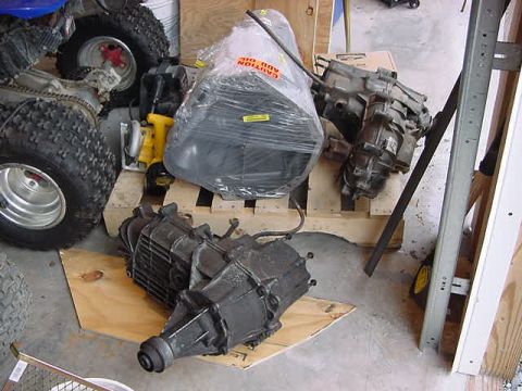 1995 Ford Bronco - A transmission is shown on a wooden pallet, with parts of an ATV visible in the background.
