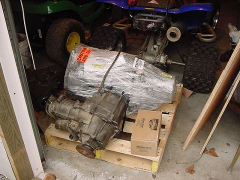 1995 Ford Bronco - Two automotive transmission and transfer case components are stored on pallets, with other vehicles in the background.