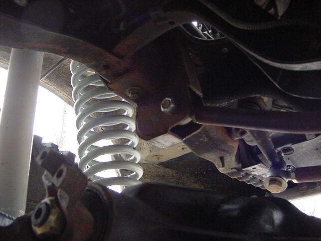 Underside view of suspension components with a white coil spring