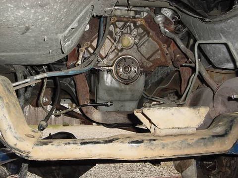 1995 Ford Bronco - Close-up of the engine bay and exhaust system from underneath a vehicle.