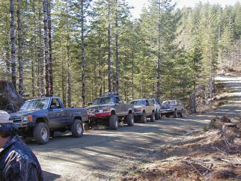 1994 Ford Explorer - Several trucks are parked on a dirt road in a wooded area, suggesting a trail or off-road excursion.