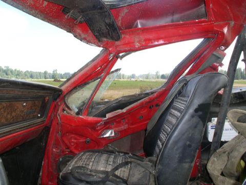 1979 Ford Bronco - The interior of a red vehicle shows significant damage to the roof and windshield structure.
