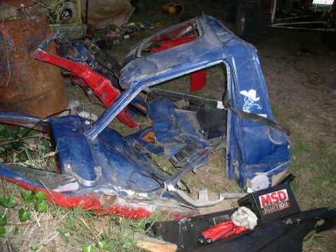 1979 Ford Bronco - The heavily damaged vehicle body lies in a grassy area, with a visible MSD Ignition box and Supermotors.net branding.