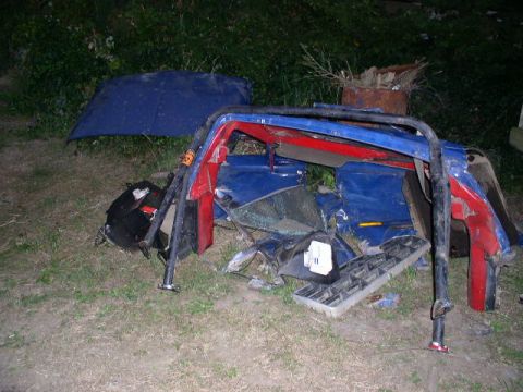 1979 Ford Bronco - Scattered parts of a vehicle, including a blue hood and a red and blue frame, are visible outdoors.