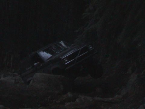 1994 Ford Explorer - A dark-colored SUV navigates a rocky path in low light conditions.