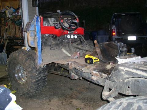 1979 Ford Bronco - A heavily modified vehicle chassis sits in a garage, with a second vehicle visible in the background.