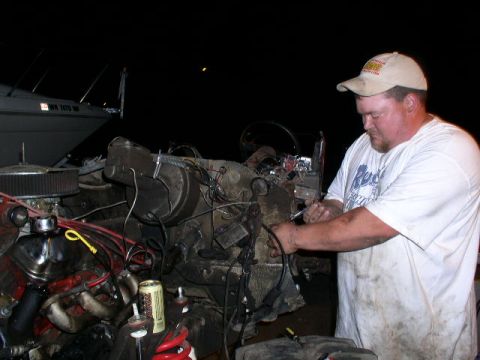 1979 Ford Bronco - A man works on a vehicle's engine bay at night, with a boat visible in the background.