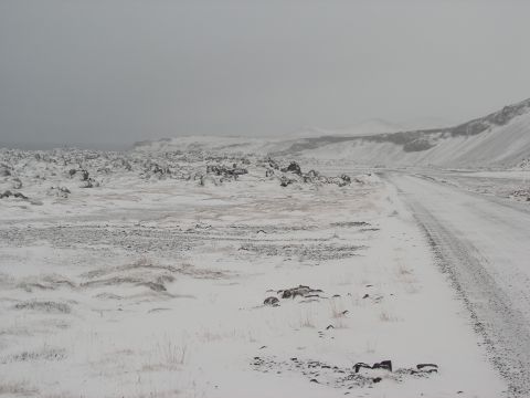 2001 Jeep Wrangler - A desolate, snow-covered landscape with a dirt road stretching into the distance, suggesting a harsh winter environment.