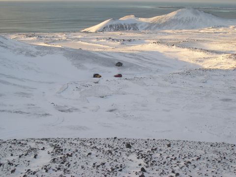 2001 Jeep Wrangler - SUVs navigate a snowy terrain under a bright sky, with distant mountains and the ocean visible.