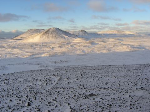2001 Jeep Wrangler - A vast, snow-covered landscape stretches towards distant, sunlit mountains under a partly cloudy sky.
