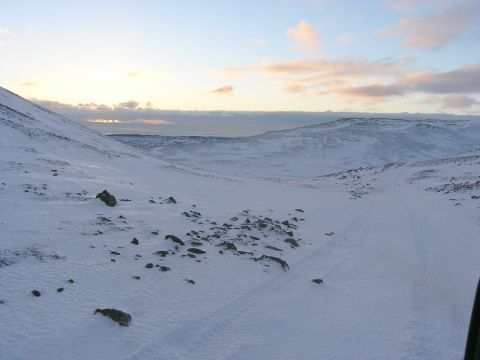 2001 Jeep Wrangler - A vast, snow-covered landscape under a pale sky, with a hint of a vehicle in the lower right corner.