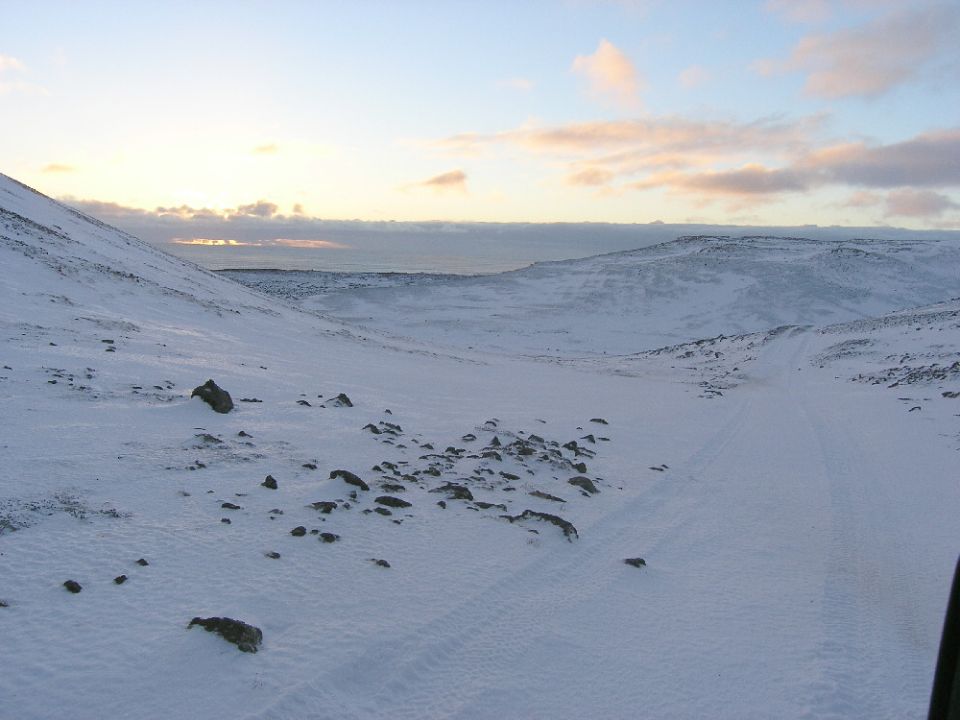 Snowy landscape with a vehicle's side mirror visible in the foreground