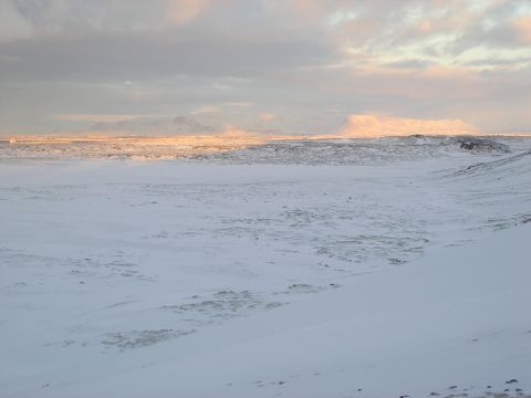2001 Jeep Wrangler - A wide, snow-covered landscape stretches towards distant, sunlit mountains under a cloudy sky.