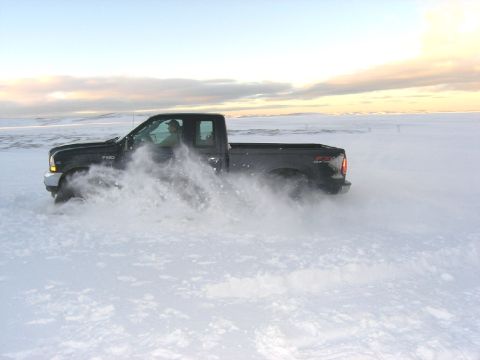 2001 Jeep Wrangler - A black 2001 Ford F-250 Super Duty pickup truck kicks up snow as it drifts across a snowy field.
