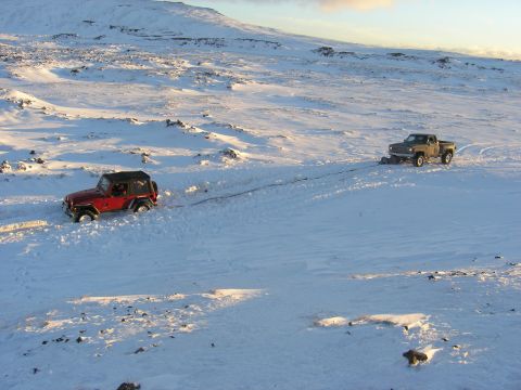2001 Jeep Wrangler - A red Jeep TJ is being towed by a pickup truck across a snow-covered landscape.