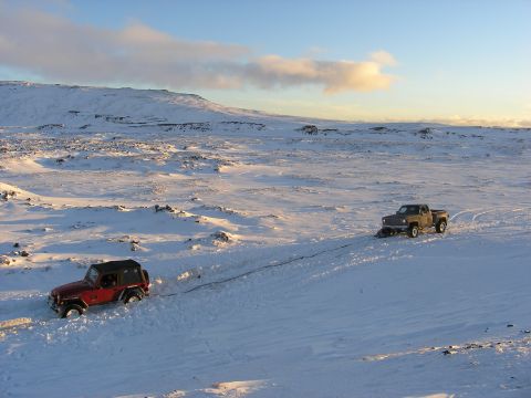 2001 Jeep Wrangler - Two vehicles navigate a snow-covered terrain, one appears to be towing the other.