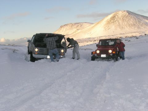 2001 Jeep Wrangler - Two vehicles are stuck in a snowy landscape, with people attempting to work on one of them.
