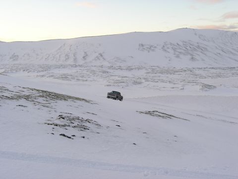 2001 Jeep Wrangler - A pickup truck navigates a vast, snow-covered terrain under a pale sky.