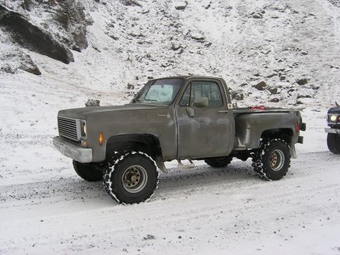 2001 Jeep Wrangler - This pickup truck is equipped with large tires for snowy conditions. Another vehicle is partially visible.