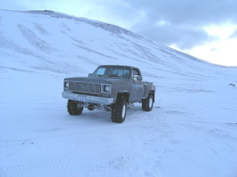 2001 Jeep Wrangler - A lifted pickup truck sits in a snowy field under a cloudy sky.
