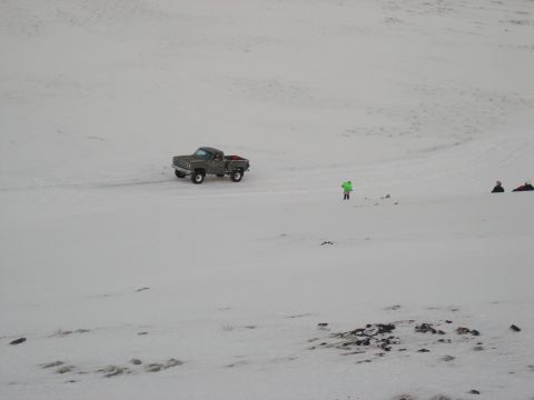 2001 Jeep Wrangler - A gray pickup truck drives across a snow-covered landscape with a lone figure in a bright green jacket observing.
