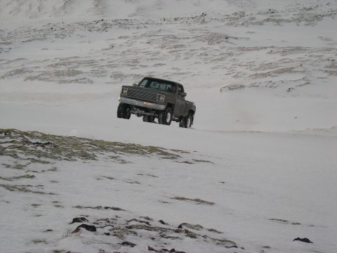 2001 Jeep Wrangler - A gray pickup truck navigates a snowy landscape, appearing to be from the early 1980s.