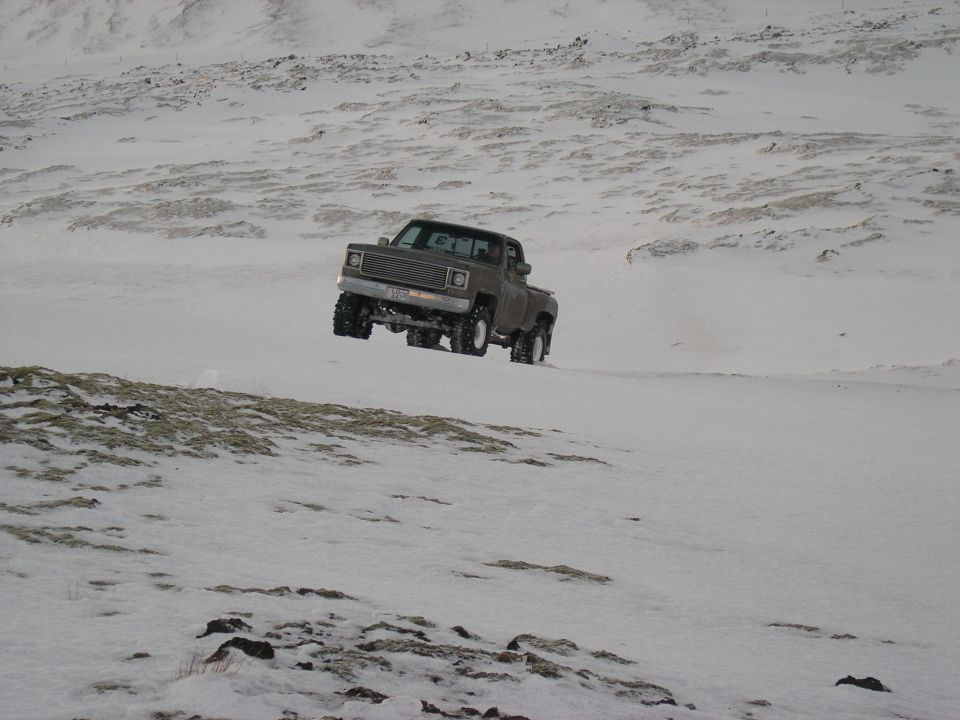 Gray pickup truck driving in snow, 1980s model