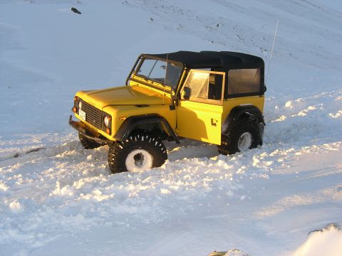 2001 Jeep Wrangler - A yellow Land Rover Defender 90 navigates through a snowy landscape.