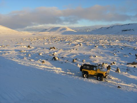 2001 Jeep Wrangler - A yellow 2001 Jeep TJ navigates a vast, snow-covered terrain under a bright blue sky.