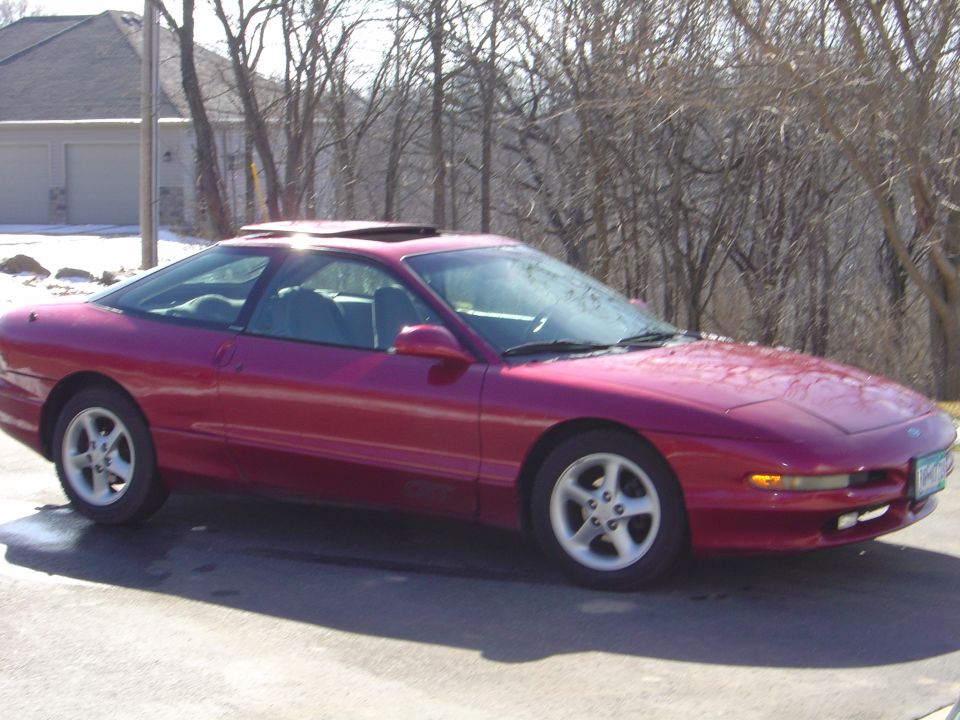 Magenta Ford Probe coupe with sunroof and alloy wheels parked on a driveway with snow patches