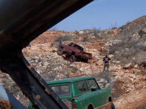 2004 Aston Martin Virage - Off-road vehicles tackle a challenging, rocky incline under a clear blue sky.