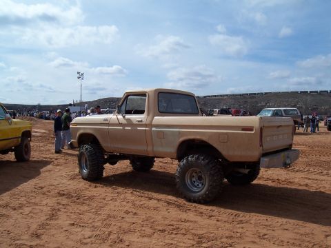 2004 Aston Martin Virage - A lifted tan Ford pickup truck sits on sandy terrain with other vehicles and spectators in the background.