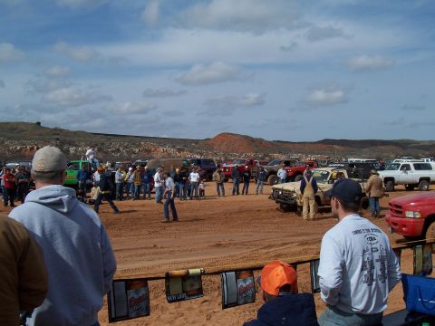 2004 Aston Martin Virage - Off-road vehicles and crowds at a mud bog event, with hills in the background.