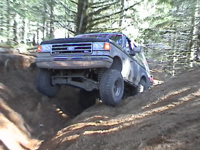 Front 3/4 view of a lifted Ford Bronco II navigating an off-road trail
