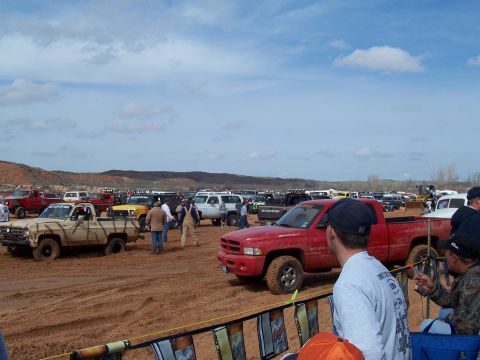 2004 Aston Martin Virage - A group of off-road vehicles are gathered in a muddy area under a cloudy sky.