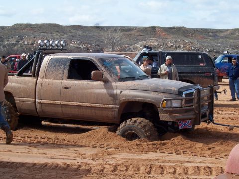 2004 Aston Martin Virage - Muddy Dodge Ram pickup truck is stuck in the sand during an off-road event.