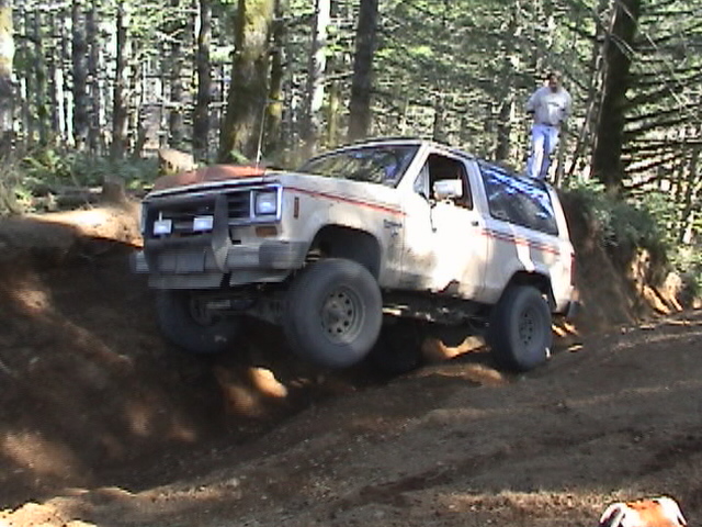 Tan off-road SUV with red and white pinstripes on a dirt trail