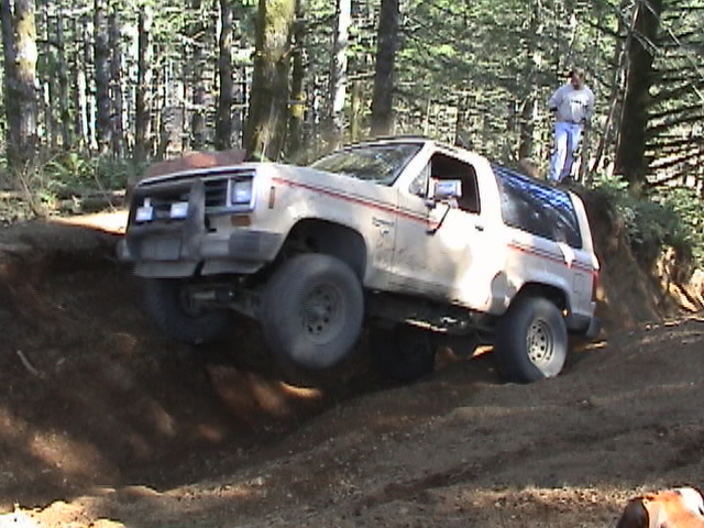 Tan off-road SUV with red pinstripes navigating a dirt trail