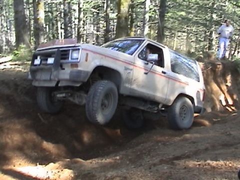 1994 Ford Explorer - White Ford Bronco II navigates a steep dirt incline during an off-road excursion.