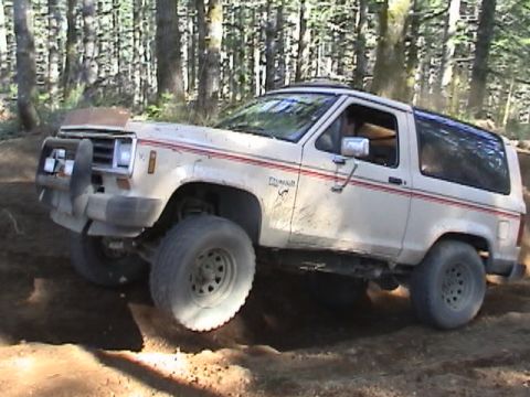1994 Ford Explorer - This lifted SUV navigates a dirt trail with large off-road tires and a protective bull bar on the front.