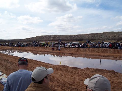 2004 Aston Martin Virage - Spectators watch a mud bog competition with numerous vehicles present along the track.