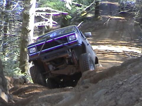 1994 Ford Explorer - A modified Ford Bronco II navigates a challenging off-road course with steep inclines and loose dirt.