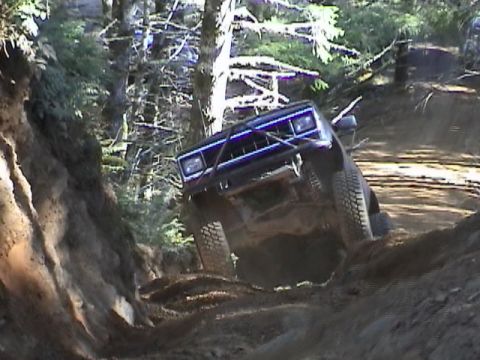 1994 Ford Explorer - An off-road vehicle navigates a challenging dirt trail in a forest setting.